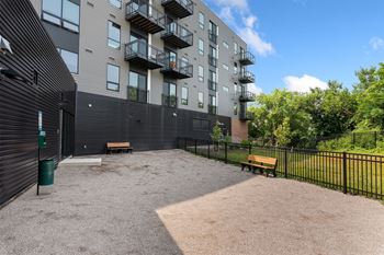 a courtyard with two benches and a trash can at the whispering winds apartments in pearland,